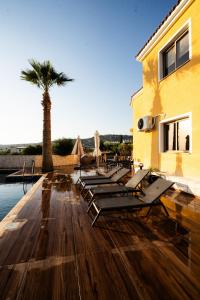 a row of chaise lounges on a wooden deck with a palm tree at Casa Alba Modern Boho Villa with private Pool near to Sea, Paphos in Peyia