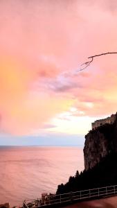 a sunset over the ocean with a castle on a cliff at Villa Grace Amalfi seaview Jacuzzi in Amalfi