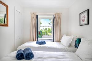 two beds in a room with a window at Idyllic Waterside Cottage in Mid Devon in Tiverton