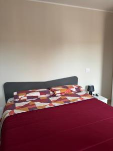 a bed with a red comforter and two pillows at Sirè House in LʼAquila