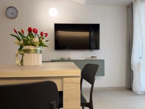 a vase of flowers on a table with a television at Ferraro Apartments in Campora San Giovanni
