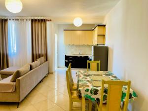 a kitchen and dining room with a table and a couch at Arc Apartment Family - City Center in Divjakë