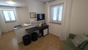 a living room with a couch and a tv and two windows at Rooms-Sobe Haus Magdalena Krk in Krk