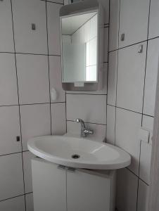 a white bathroom with a sink and a mirror at Gemütliches Zimmer in der modernen Ferienwohnung Schwalbennest im EG links in Sachsenheim +11 photos