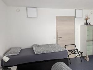 a small bedroom with a bed and a chair at Gemütliches Zimmer in der modernen Ferienwohnung Schwalbennest im EG links in Sachsenheim