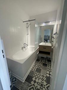 a white bathroom with a tub and a sink at - Le Belvédère - in Turckheim