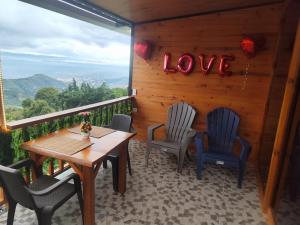 a porch with a table and chairs and a sign that says love at Glamping NOVA VILLA EL EDEN in Cali +2 photos