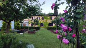 a garden in front of a house with pink roses at Villa La Ginestra - Charming Country Home in Capolona