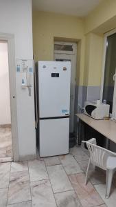 a white refrigerator in a kitchen with a table at Лидер Хаус хостел in Varna City