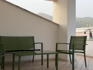 two green chairs and a table in a room at Ferraro Apartments in Campora San Giovanni