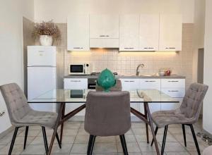 a kitchen with a glass table with chairs and a refrigerator at Maison RG in Torre Canne