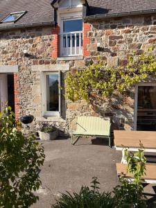 a green bench in front of a brick building at L'abri côtier du Vivier in Le Vivier-sur-Mer