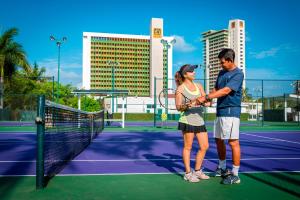 a man and a woman standing on a tennis court at El Cid Granada Hotel & Country Club in Mazatlán