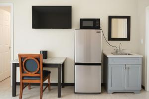a kitchen with a refrigerator and a table and a chair at Beachside Resort in Wildwood