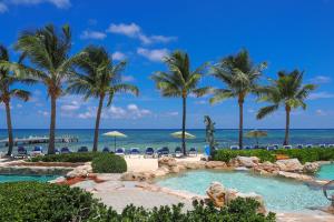 a resort with a pool and palm trees and the ocean at The Reef Beach Resort, East End, Grand Cayman in Sand Bluff