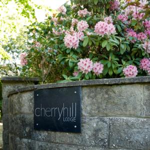a sign on a stone wall with pink flowers at Cherryhill Lodge in Newcastle