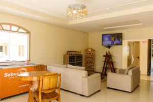 a living room with two couches and a tv at Paramirim Palace Hotel in Paramirim