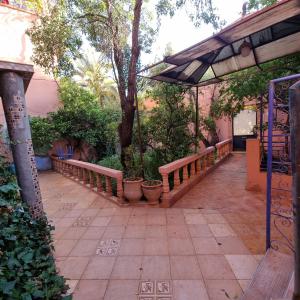 a patio with benches and trees and a fence at Momo's villa 2nd room in Aït Ourir