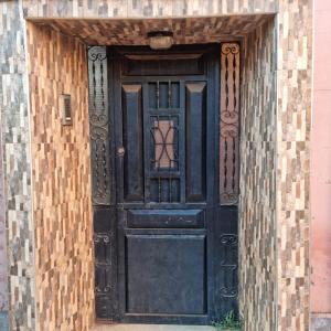an entrance to a black door with a brick wall at Momo's villa 2nd room in Aït Ourir