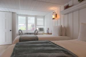 a white bedroom with two beds and a table at Marginal Way House in Ogunquit