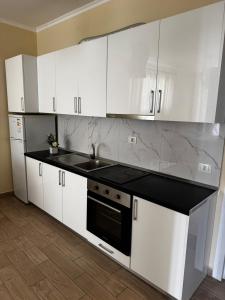 a kitchen with white cabinets and a black counter top at Inis apartamans -50 m from beach in Shëngjin