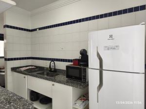 a kitchen with a white refrigerator and a sink at Apart Hotel 48 in Mogi das Cruzes