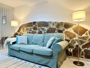 a blue couch in a room with a stone wall at BellaVista DM private pool in San Bartolomé