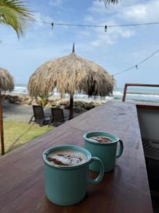two cups of coffee sitting on a table near the beach at Cosamui Beach House in San Bernardo del Viento