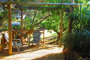 una terraza de madera con 2 sillas y una pérgola en La Nueva Ensenada en La Paloma