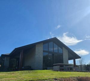 a large building with windows on a grass field at Riverside Retreat in Twizel