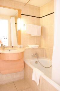 a bathroom with a tub and a sink at Central Hotel in Créteil