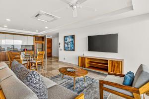 a living room with a couch and a tv at Modern condo with ocean views, rooftop infinity pool & central AC in Puerto Vallarta