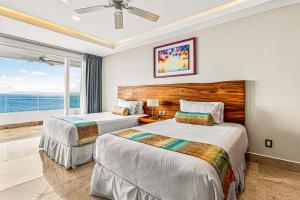 two beds in a hotel room with a view of the ocean at Modern condo with ocean views, rooftop infinity pool & central AC in Puerto Vallarta +23 photos