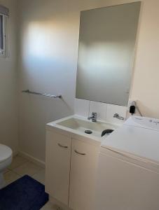 a white bathroom with a sink and a mirror at Coronet Bay Beach Cabin in Coronet Bay +5 photos