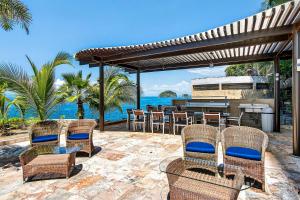a patio with chairs and a table with a view of the ocean at Modern condo with ocean views, rooftop infinity pool & central AC in Puerto Vallarta