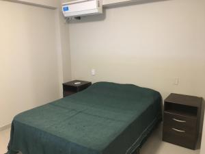 een slaapkamer met een groen bed en 2 nachtkastjes bij Apartamento Catalina Sur in San Miguel de Tucumán