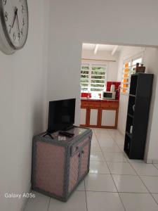 a living room with a tv and a clock on a wall at Chez COCO in Le Gosier