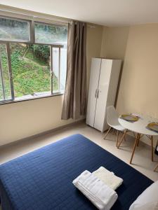a bedroom with a blue bed and a table at Studio 302 Centro Imperial in Petrópolis
