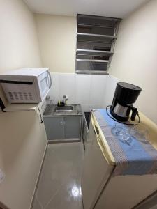 a small kitchen with a microwave and a sink at Studio 302 Centro Imperial in Petrópolis
