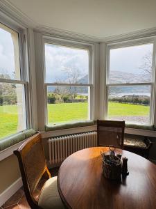 a dining room with a table and two windows at Cuilcheanna House - near Glencoe - room only or breakfast available in Onich