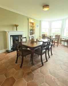 a dining room with a table and chairs and a fireplace at Cuilcheanna House - near Glencoe - room only or breakfast available in Onich