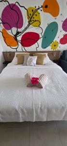 a bedroom with a white bed with a flower mural at STUDIO La Diamantinoise in Le Diamant +12 photos