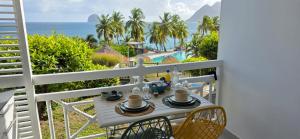 a table on a balcony with a view of the ocean at STUDIO La Diamantinoise in Le Diamant