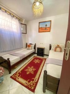 a room with two beds and a couch and a rug at Dallas Surf Apartment in Agadir