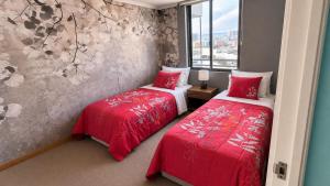 two beds in a room with red sheets at Departamentos Mar Egeo in Iquique +7 photos