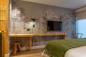a bedroom with a desk and a tv on a wall at Hotel Gran Wolf - Haras Santa Amelia in Negrete +10 photos