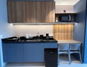 a kitchen with a sink and a counter with two chairs at Flat Beach Class Meireles in Fortaleza