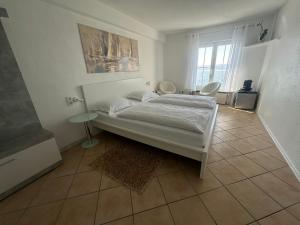 a white bedroom with a bed and a window at Hotel la Perla in Meersburg
