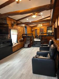 a living room with leather furniture and a ceiling fan at Beautiful cabin surrounded by nature in Catskill