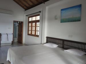 a bedroom with a large white bed with a window at Paradise Bay in Beruwala +75 photos